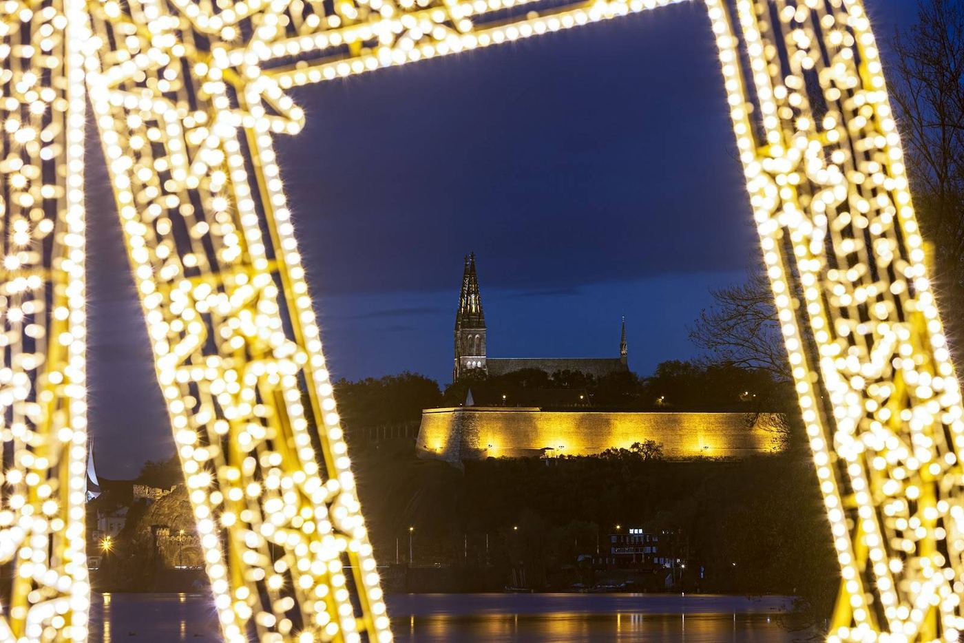 Průhled skrze světelnou hvězdu na osvětlený Vyšehrad nad řekou v noci